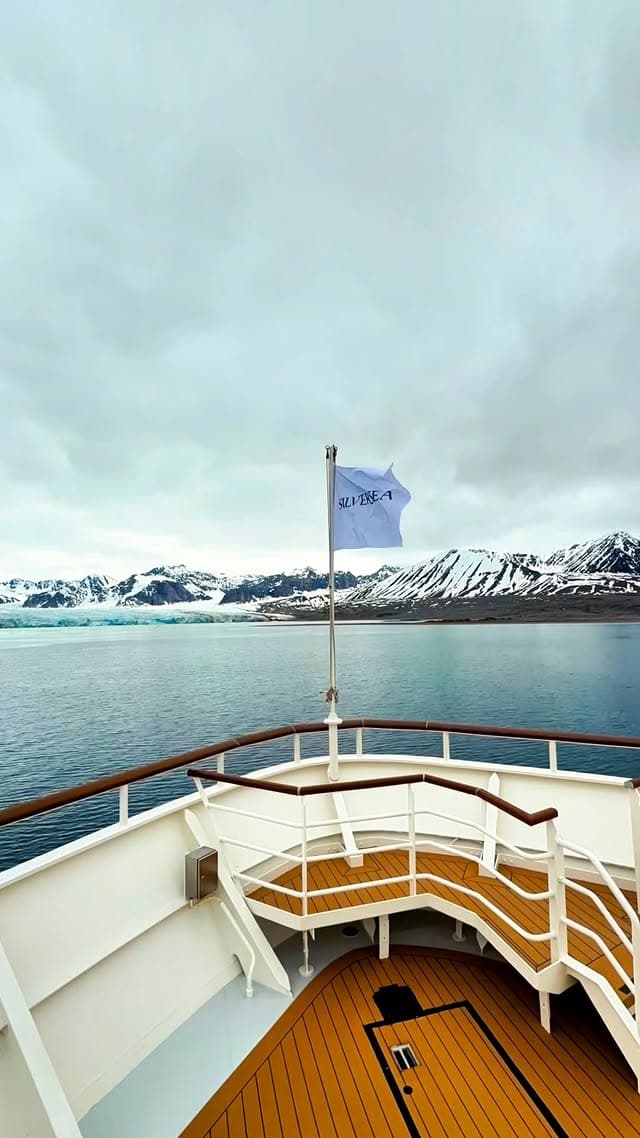 Expedition cruise ship sailing through Alaskan waters with snow-capped mountains