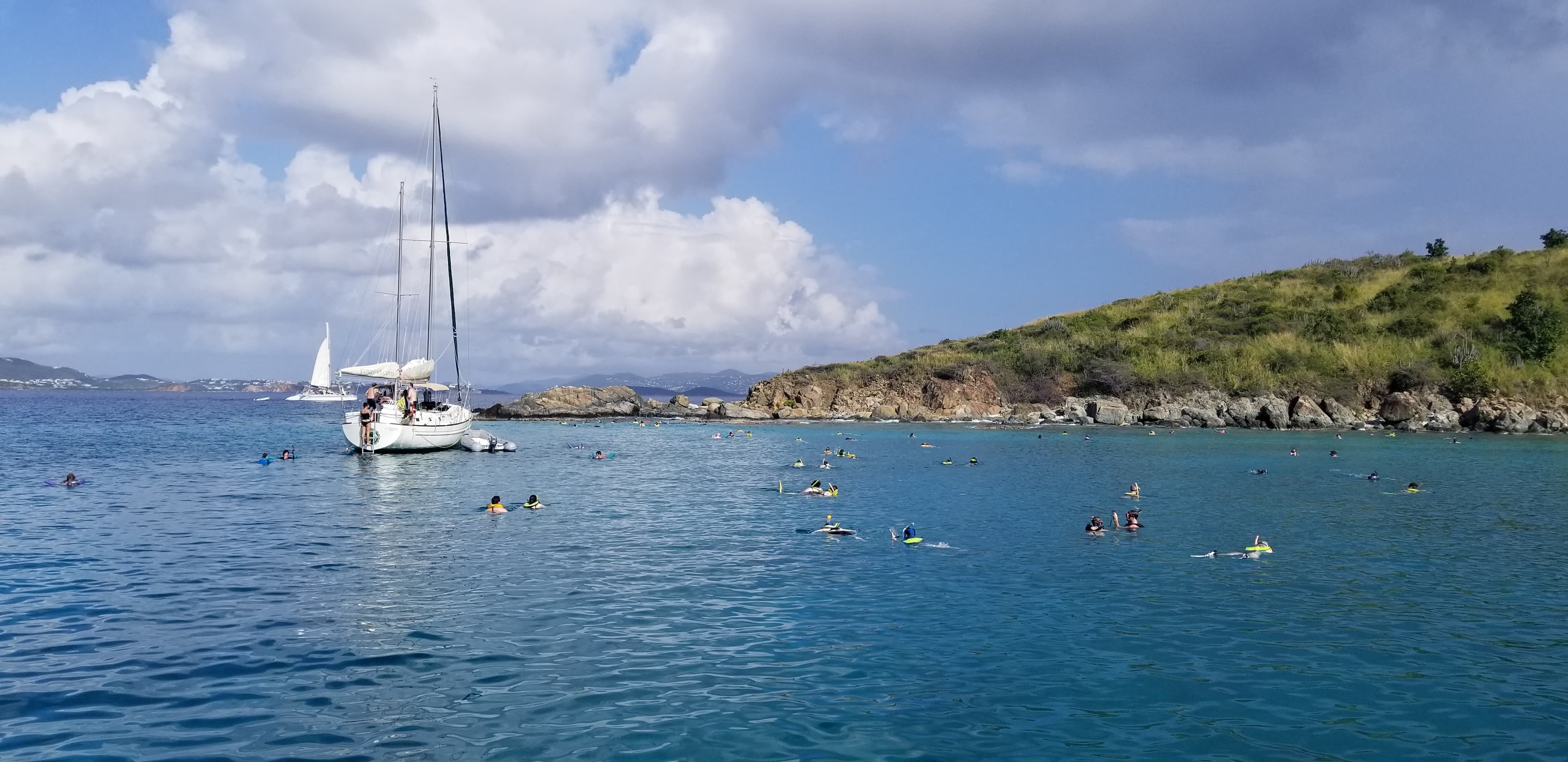 Snorkelers and a sailboat in the crystal-clear waters of Turtle Cove, St. Thomas